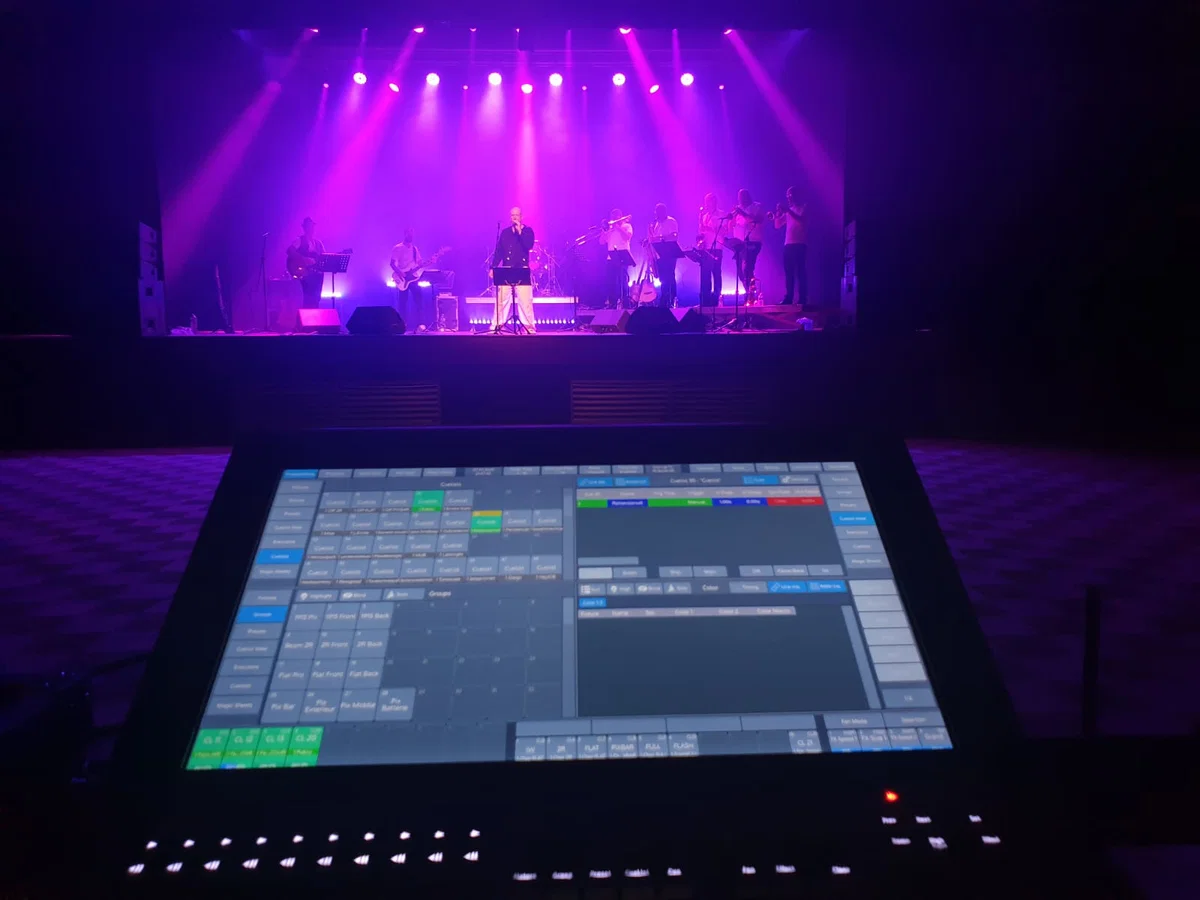 Pupitre ETC Eos en régie face au plateau éclairé en violet